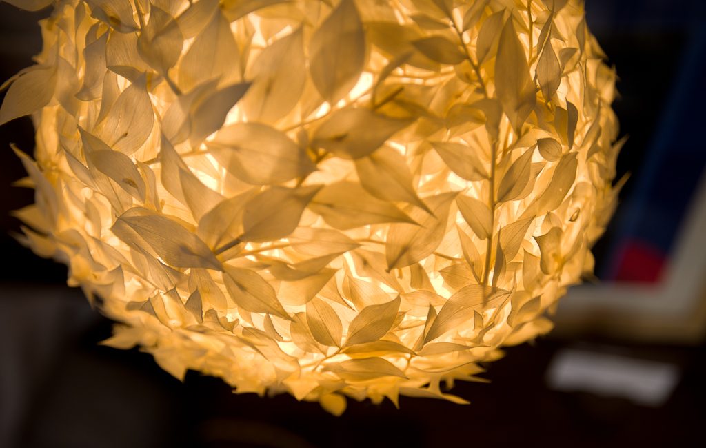 Detalle de una lámpara esférica de hojas encendida