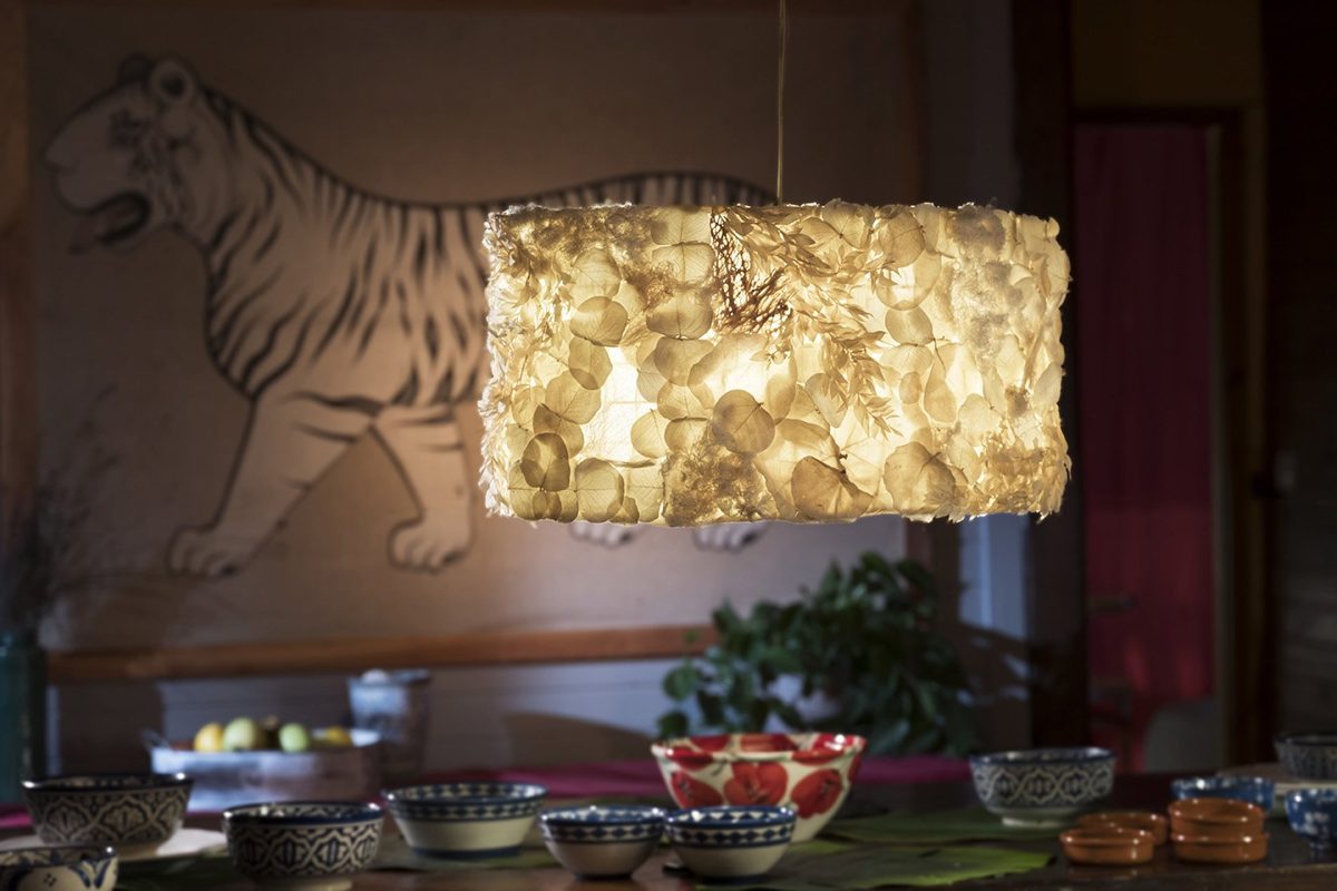 Lámpara Humbaba cilíndrica colgada ante un mural de tigre