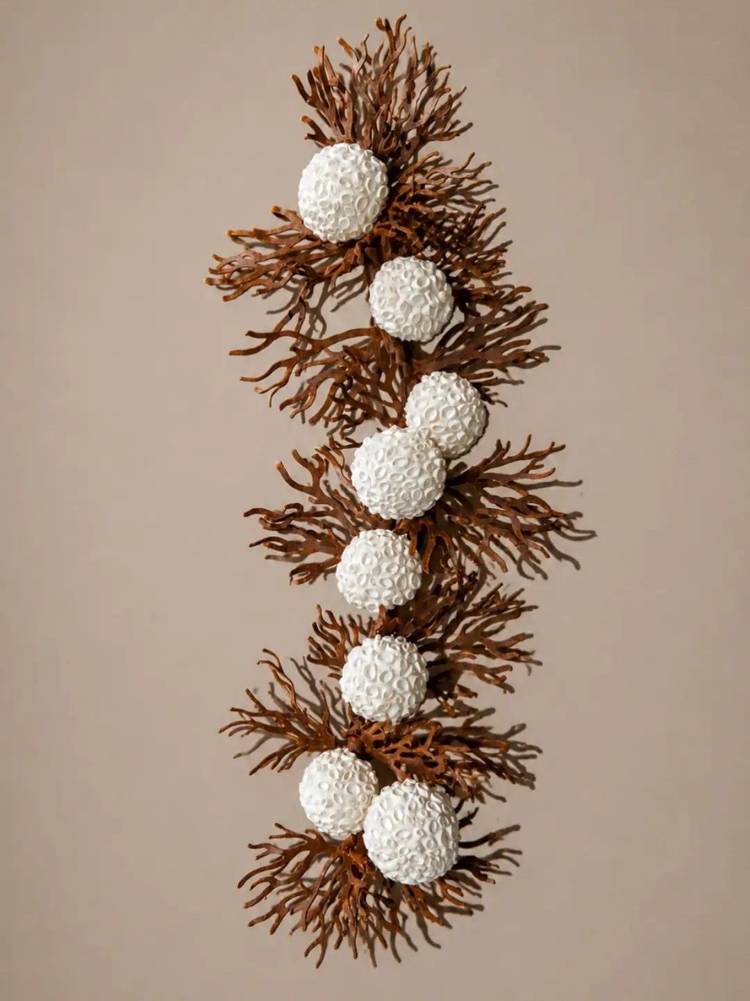 Escultura de pared de bolas blancas sobre ramas de coral de cobre